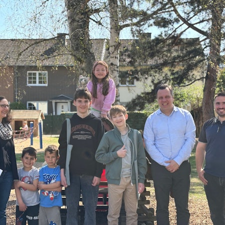 Kinder, Jugendliche und Erwachsene posieren draußen an einem Spielplatz.