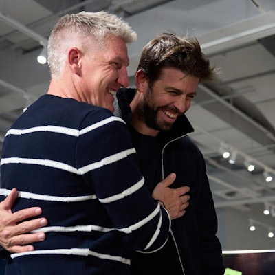 Zwei Männer stehen nebeneinander und lachen.