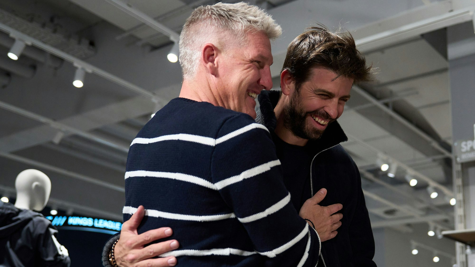 Zwei Männer stehen nebeneinander und lachen.