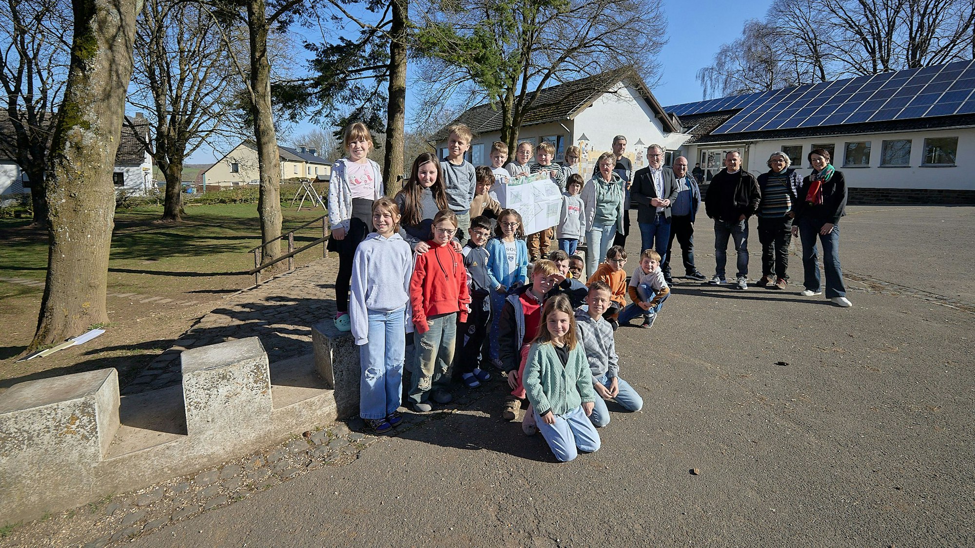 Eine Gruppe Menschen steht auf dem Schulhof in Marmagen.