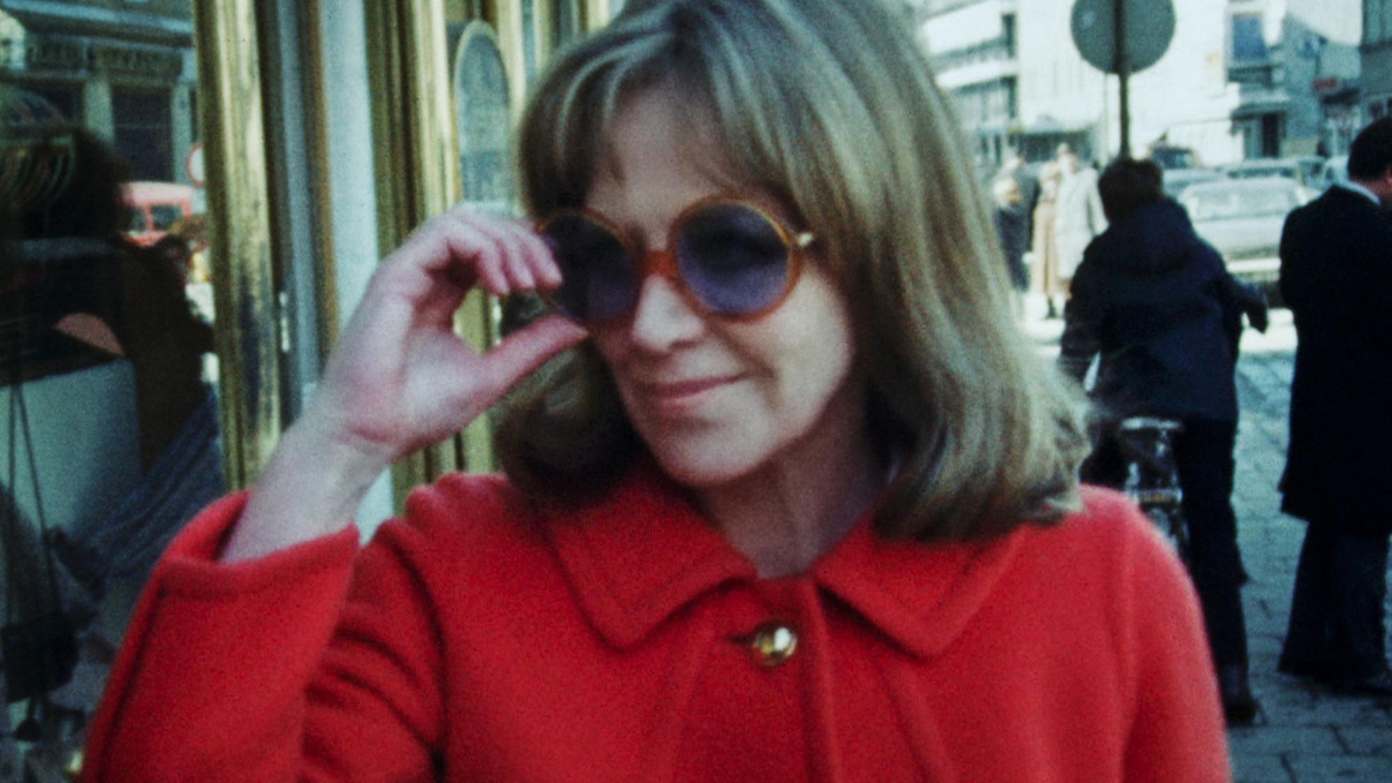 Hildegard Knef in den 1970er Jahren mit rotem Stoffmantel und großer Sonnenbrille.