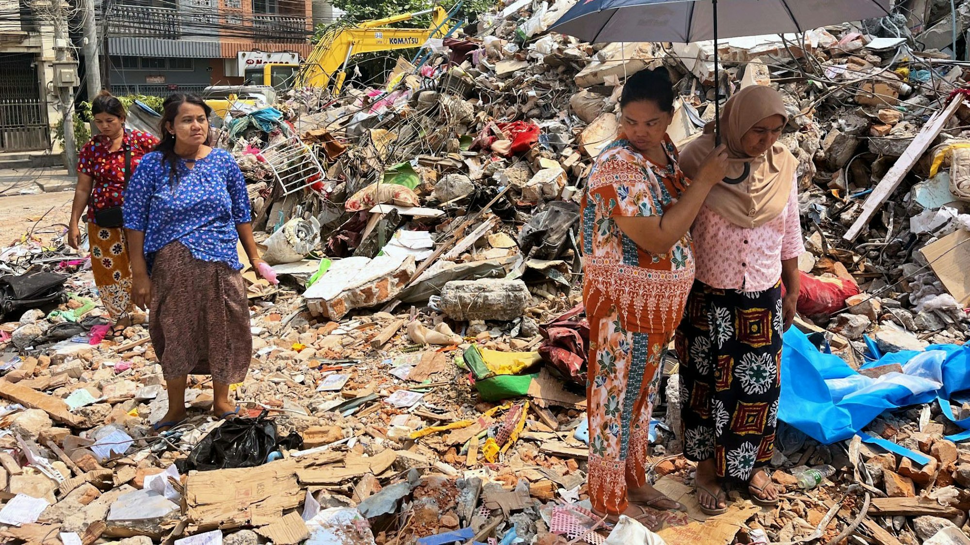 Menschen in Myanmar halten sich vor ihrem beim Erdbeben eingestürzten Haus auf. Foto: -/kyodo/dpa +++ dpa-Bildfunk +++