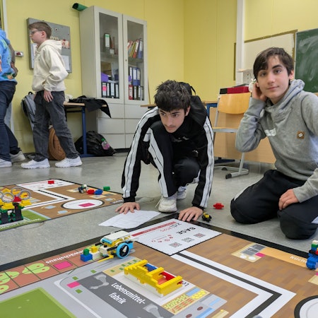 Zwei Schüler bereiten einen Lego-Roboter auf einen Wettkampf vor.