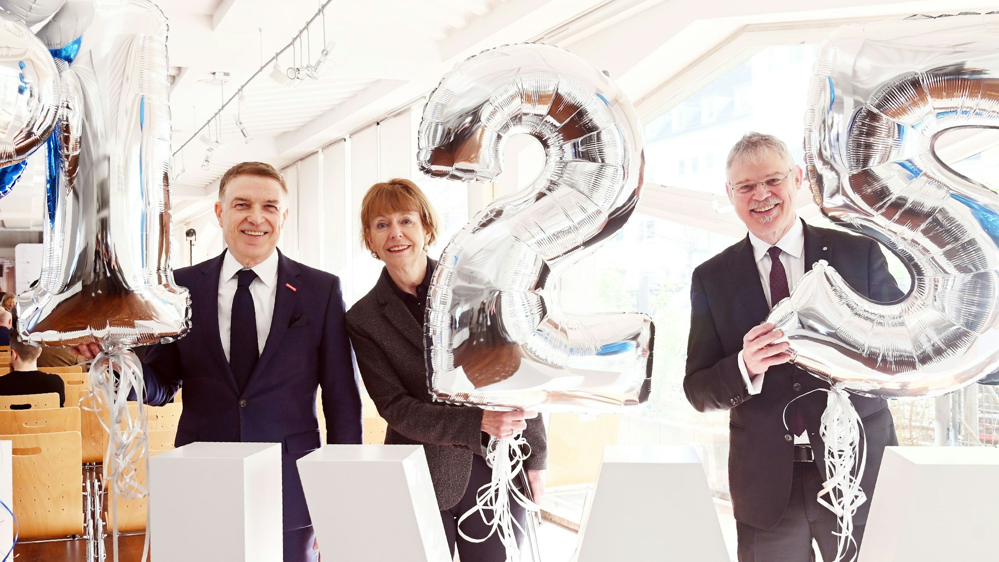 Hauptgeschäftsführer Erik Werdel, Oberbürgermeisterin Henriette Reker, und Ulrich Soenius, Direktor des Kölner Wirtschaftsarchivs, halten Luftballons hoch, die die Zahl 125 zeigen.