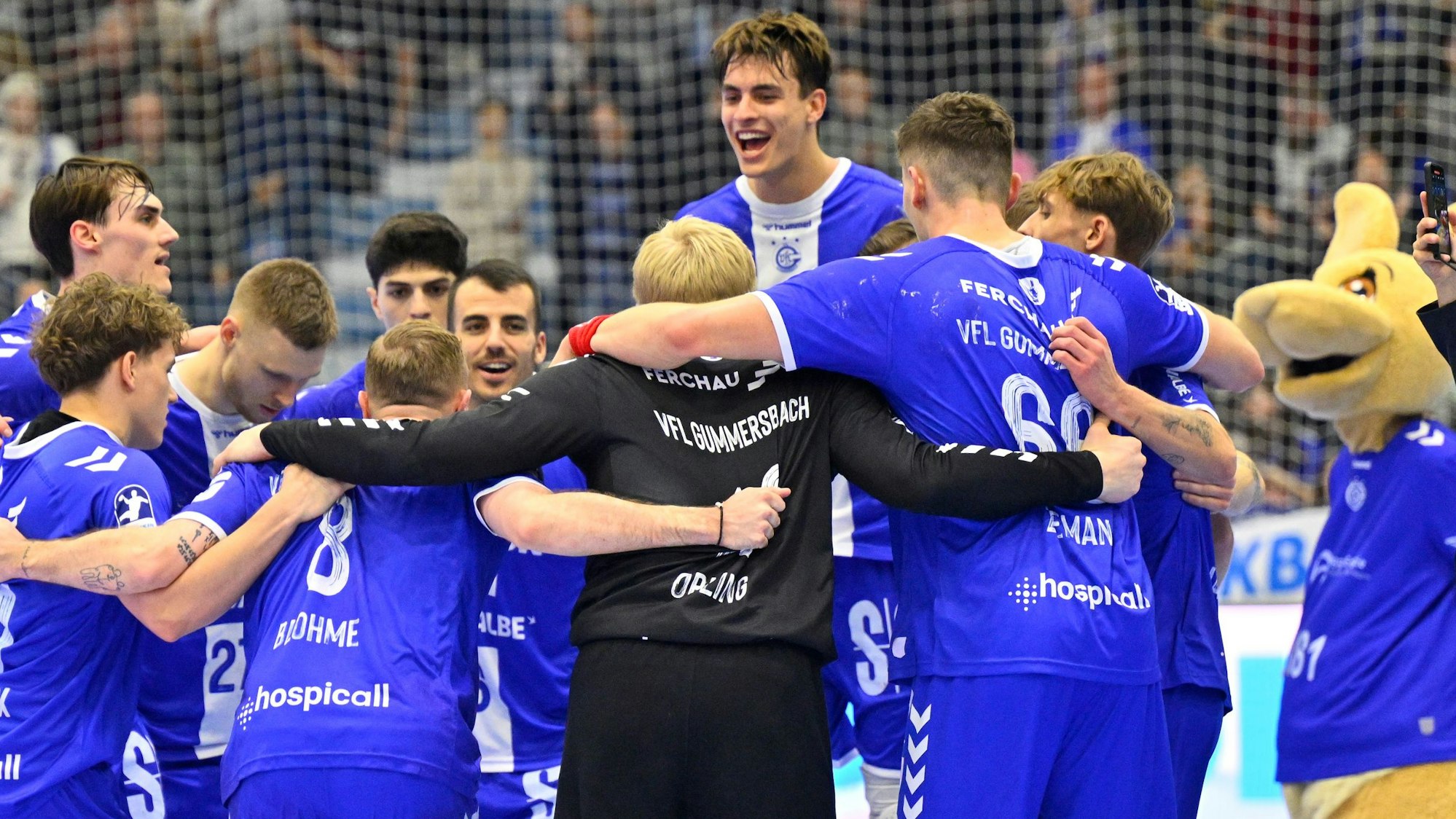 Mehrere Spieler des VfL Gummersbach und Maskottchen Gummi jubeln nach einem Handballspiel.