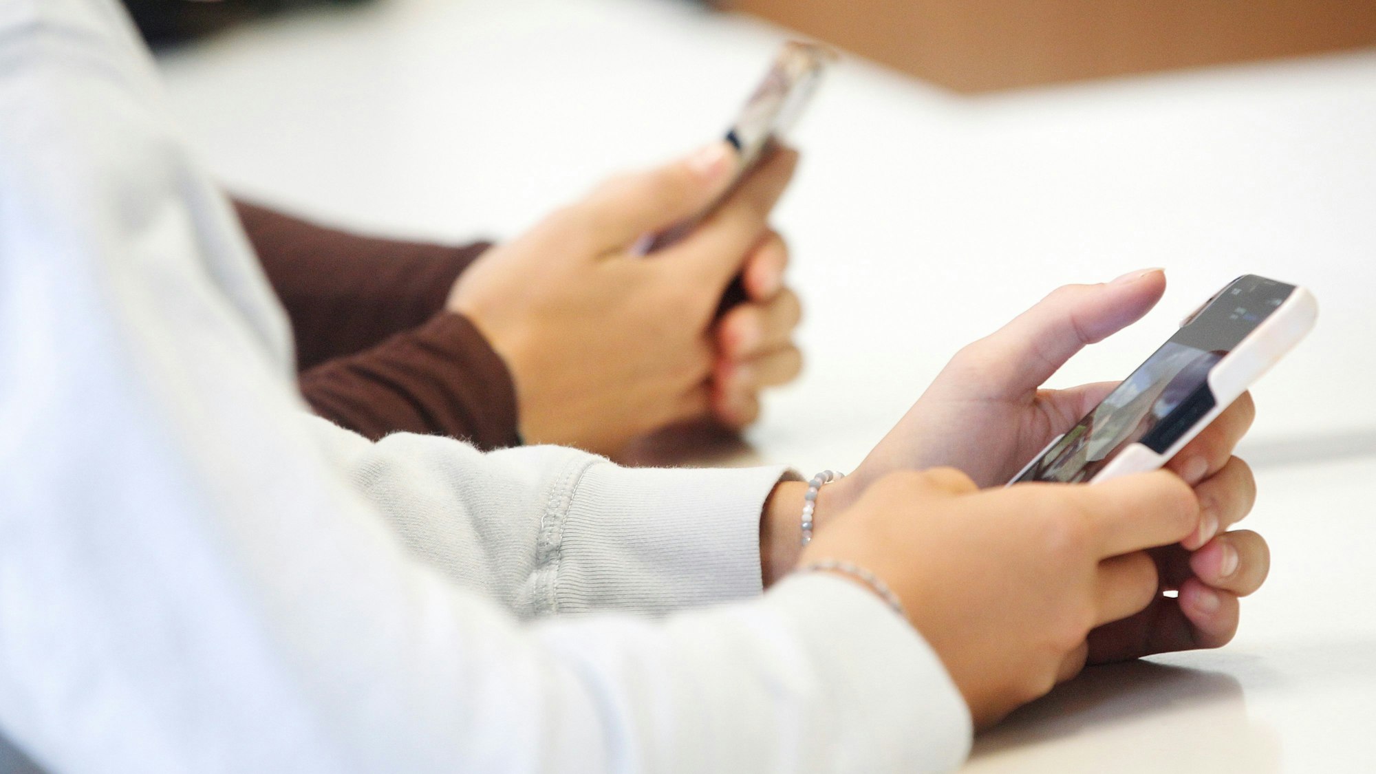 Schülerinnen benutzen ihr Smartphone im Unterricht.