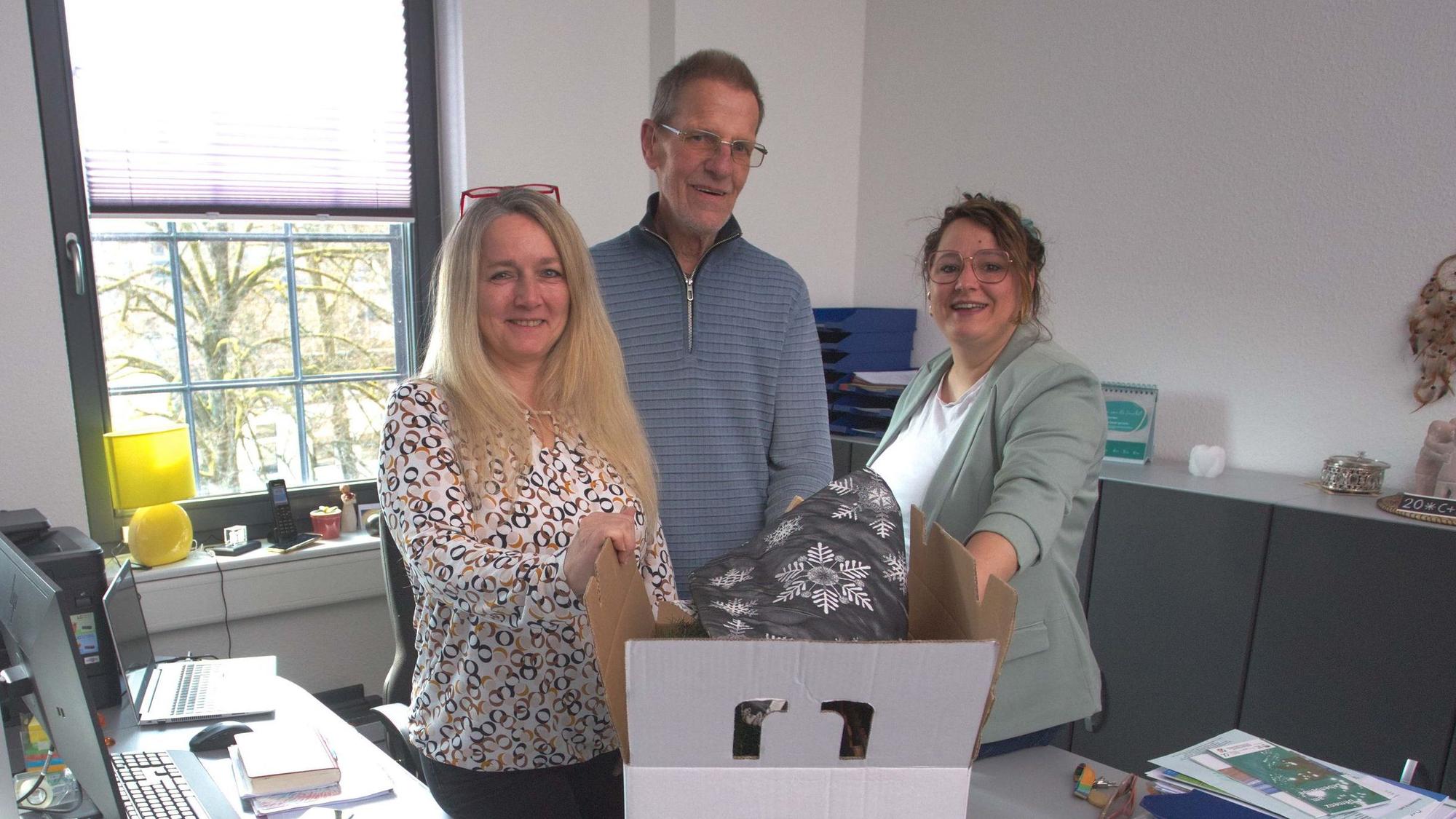 Zwei Frauen und ein Mann stehen zusammen in einem Büro.
