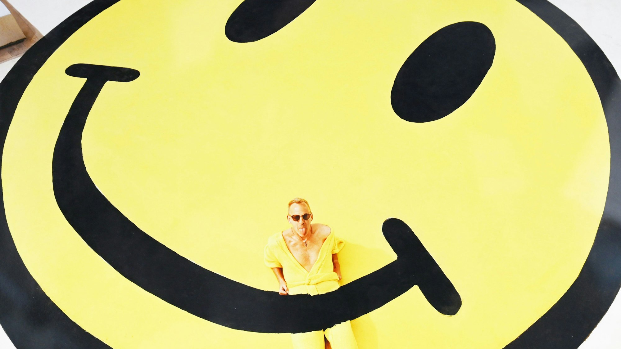 Foto von Joseph Ford mit dem britischen Musiker Fatboy Slim: Er trägt ein gestricktes Kleidungsstück, das sich nahtlos in den Smiley auf seinem Dach in Brighton einfügt. Arbeitsaufwand für das Bild: 68 Stunden.