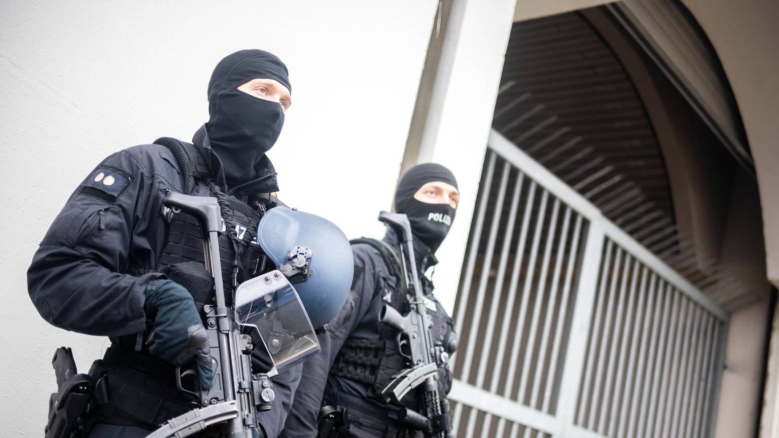 Bewaffnete Einsatzkräfte stehen vor einem Toreingang. (Symbolbild)