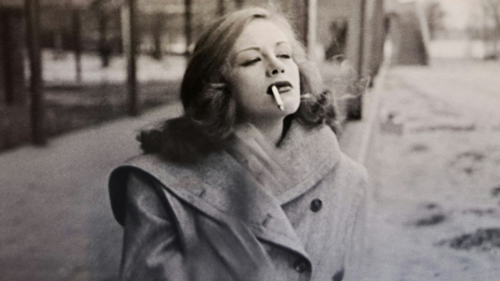 Die junge Hildegard Knef spaziert rauchend über eine winterliche Straße.