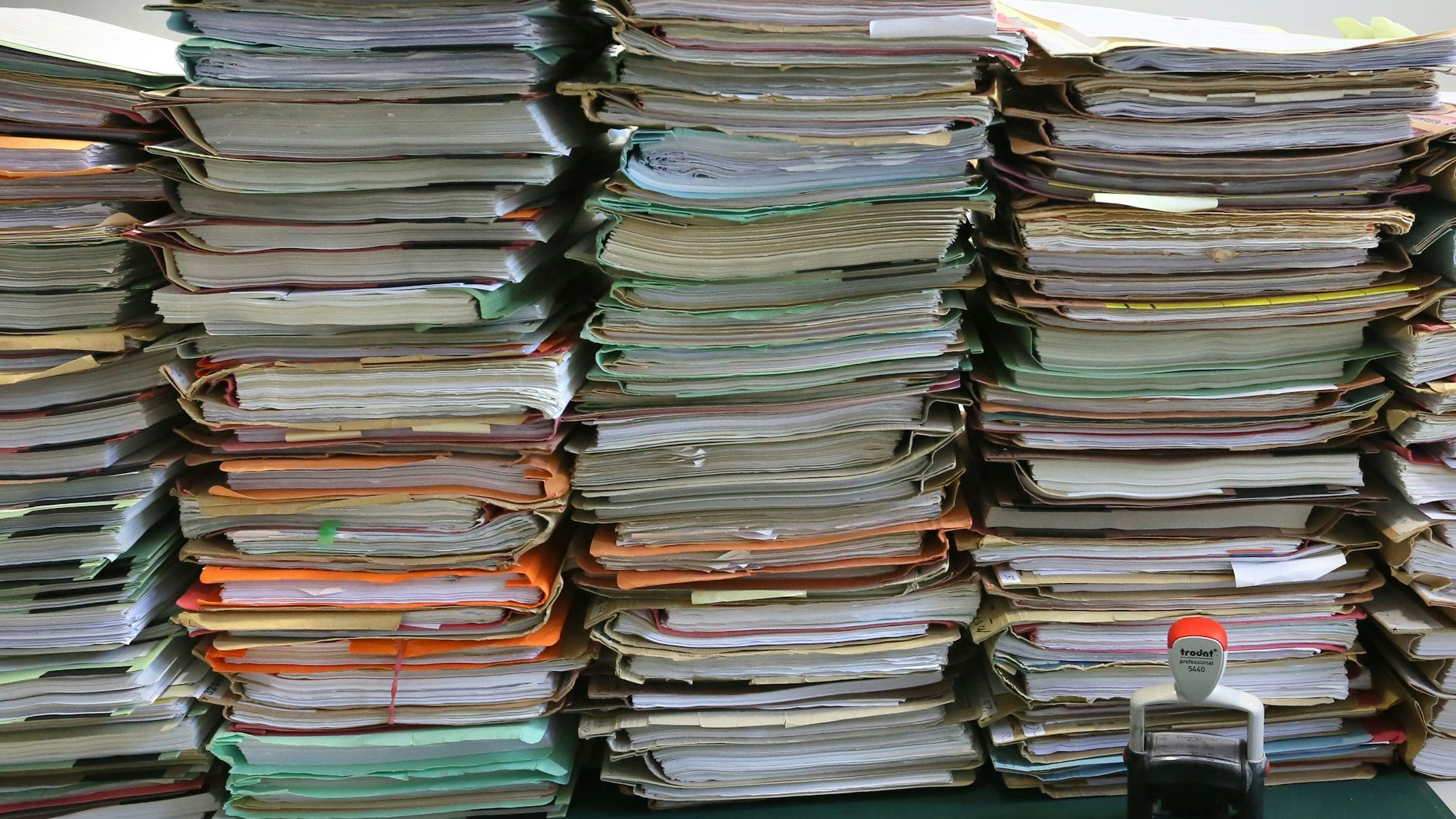 Stapel mit Akten liegen auf einem Schreibtisch.