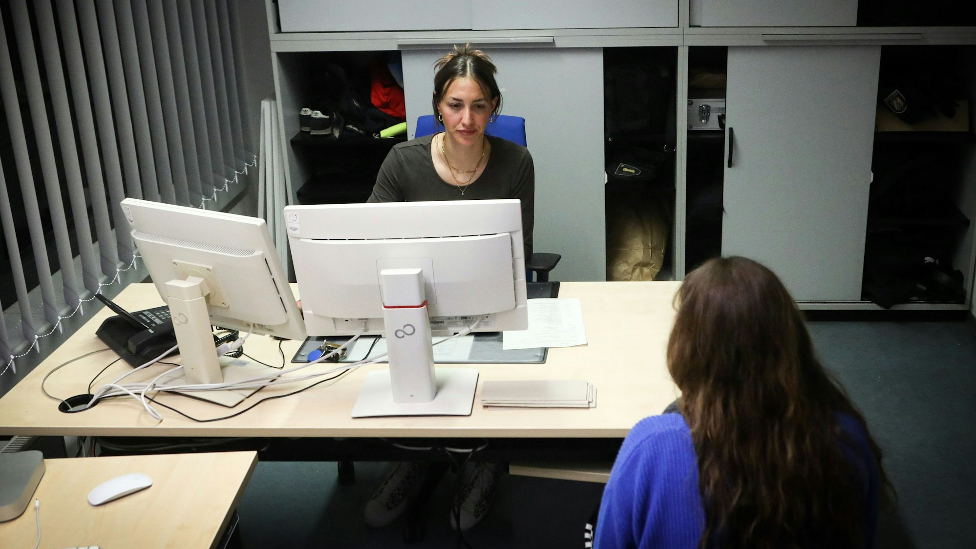 28.03.2025, Köln: Kommissarin Carina sitz hinter einem Schreibtisch, ihr gegenüber, mit dem Rücken zur Kamera, sitzt eine Zeugin.