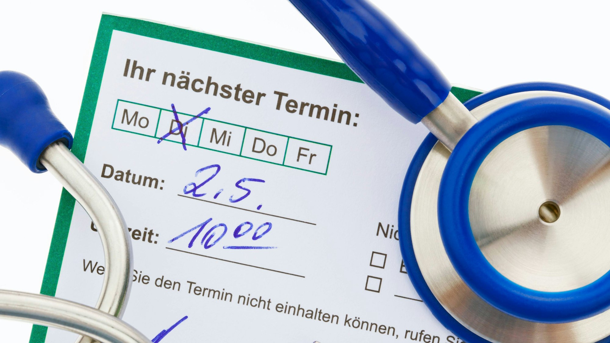 Auf einem Terminvordruck ist ein Termin für einen Arzttermin handschriftlich angekreuzt und notiert; auf dem Zettel liegt ein Stethoskop.