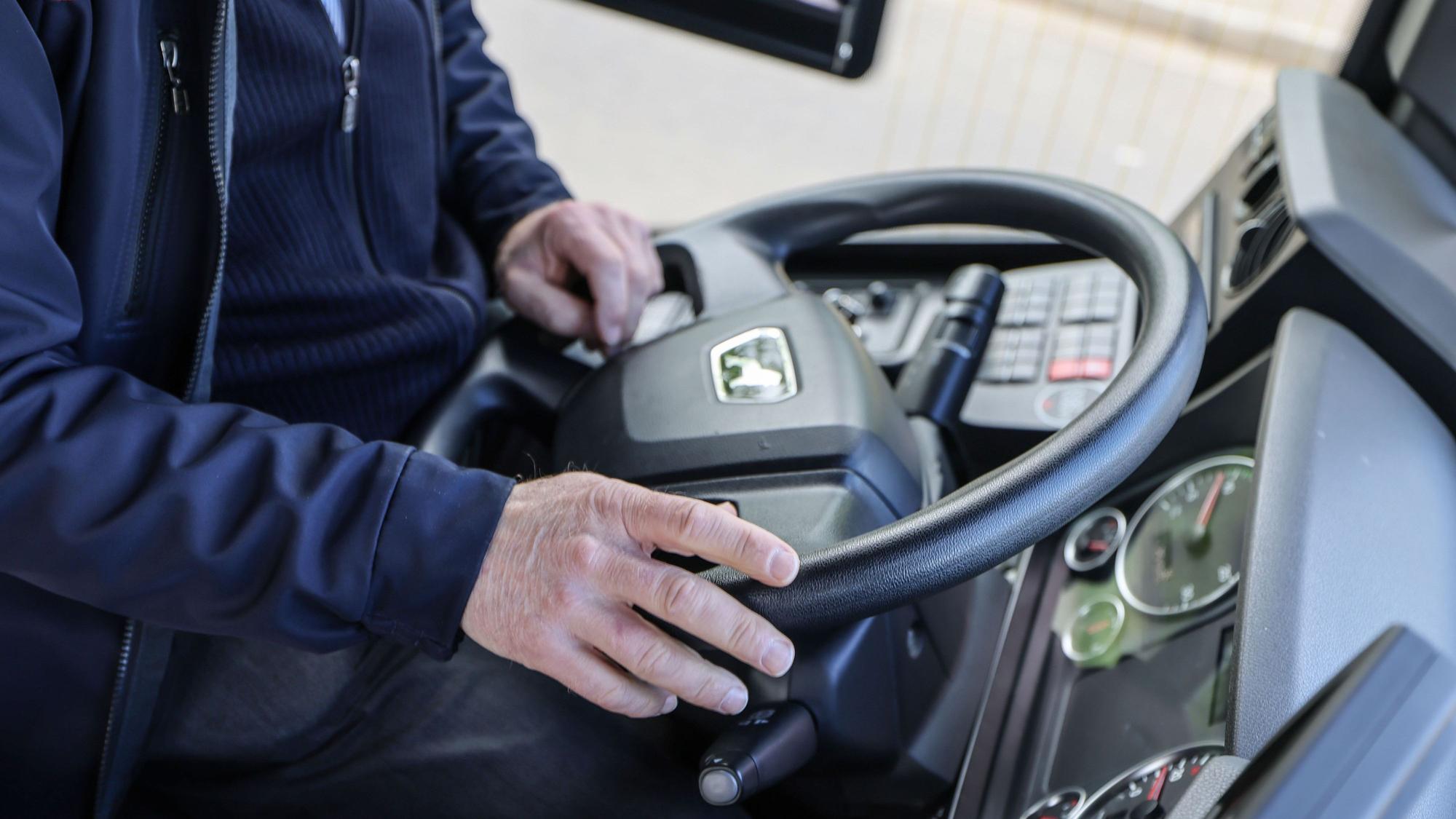 Man sieht die Hände eines Busfahrers auf dem Lenkrad.