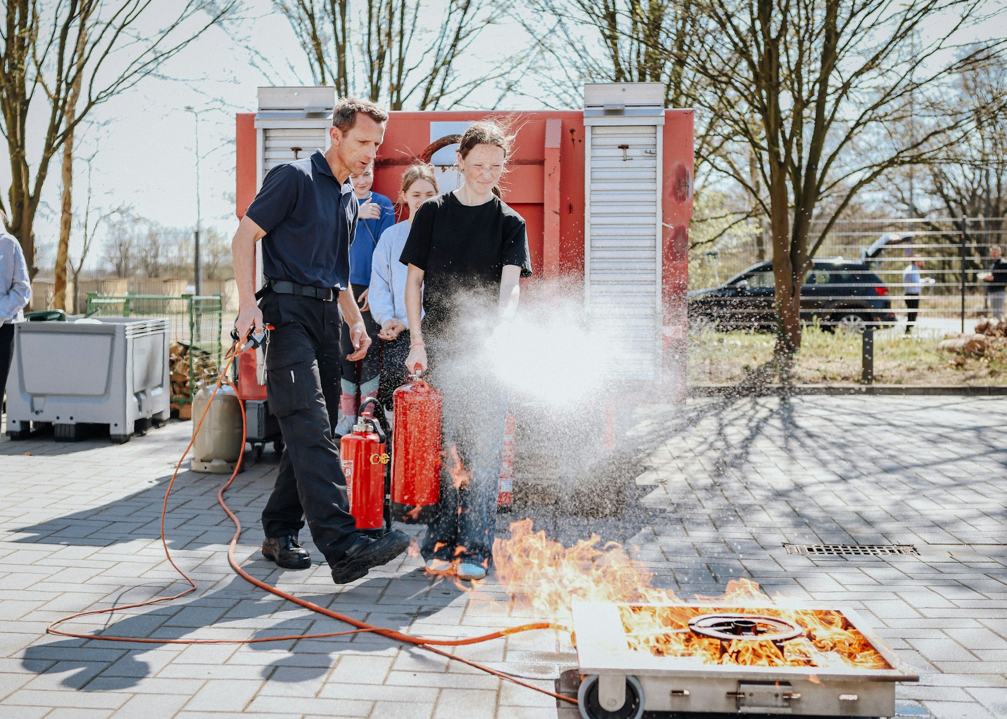 Feuerwehrmann Jörg Hempel zeigt den Mädchen, den Umgang mit einem Feuerlöscher.