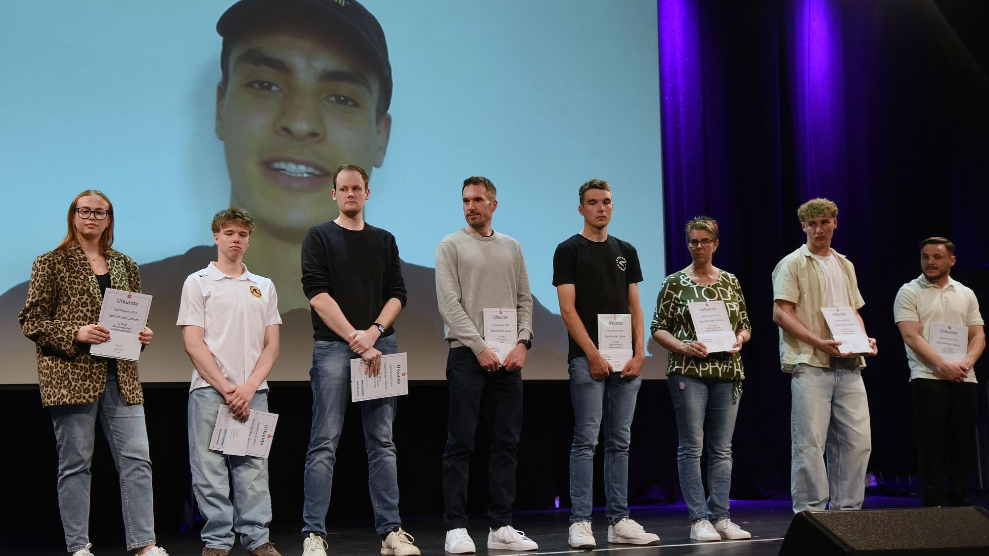 Gruppenfoto mit Sportlern, im Hintergrund eine Leinwand.