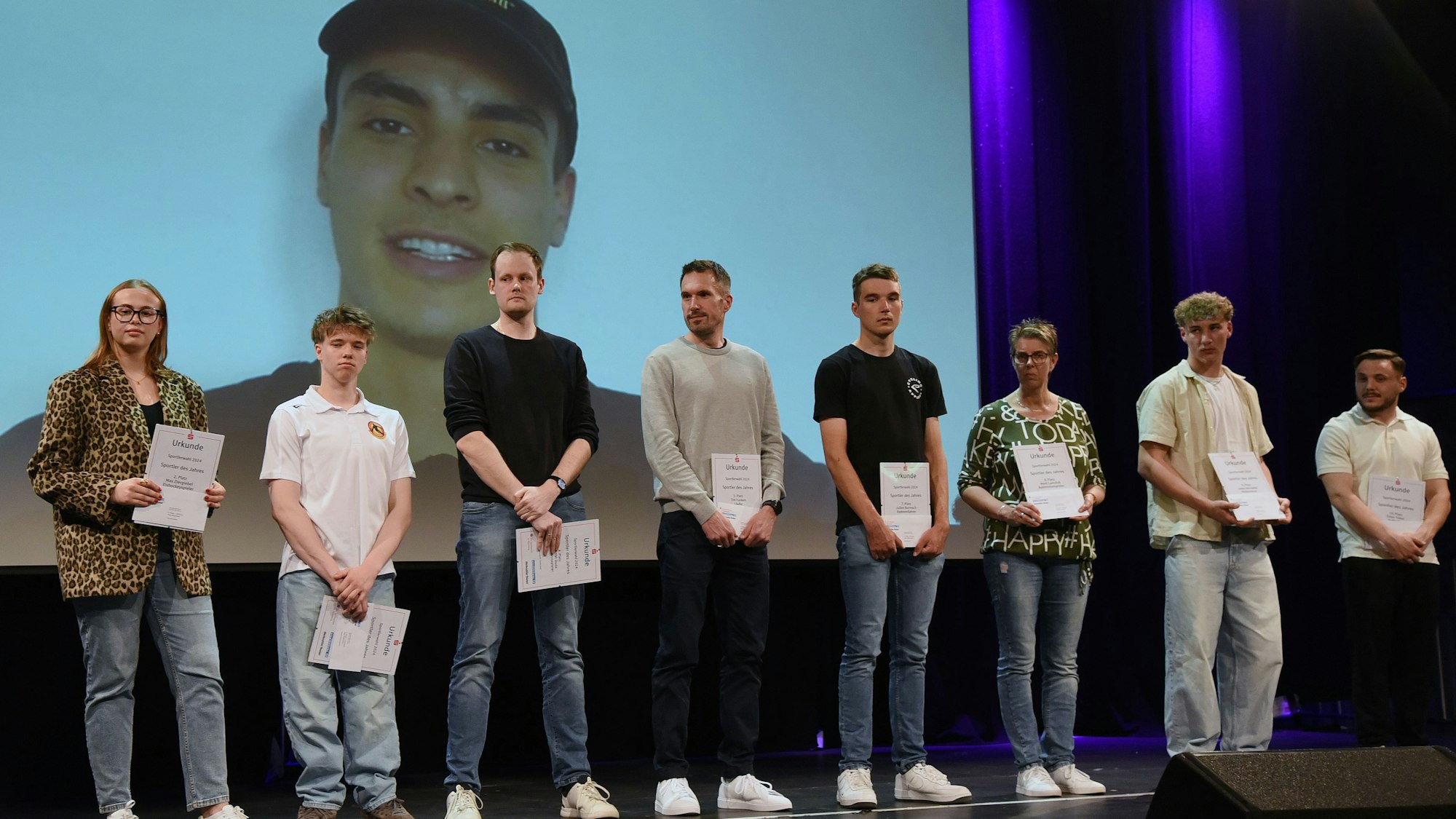 Gruppenfoto mit Sportlern, im Hintergrund eine Leinwand.