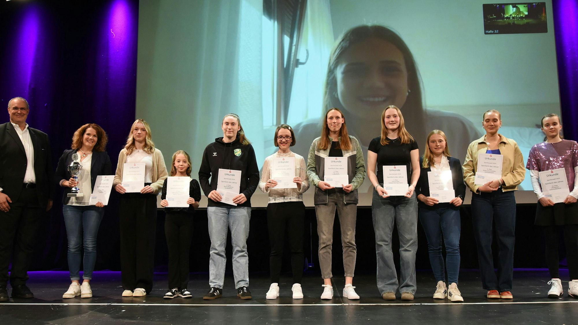 Blick auf geehrte Sportlerinnen, im Hintergrund eine Leinwand.