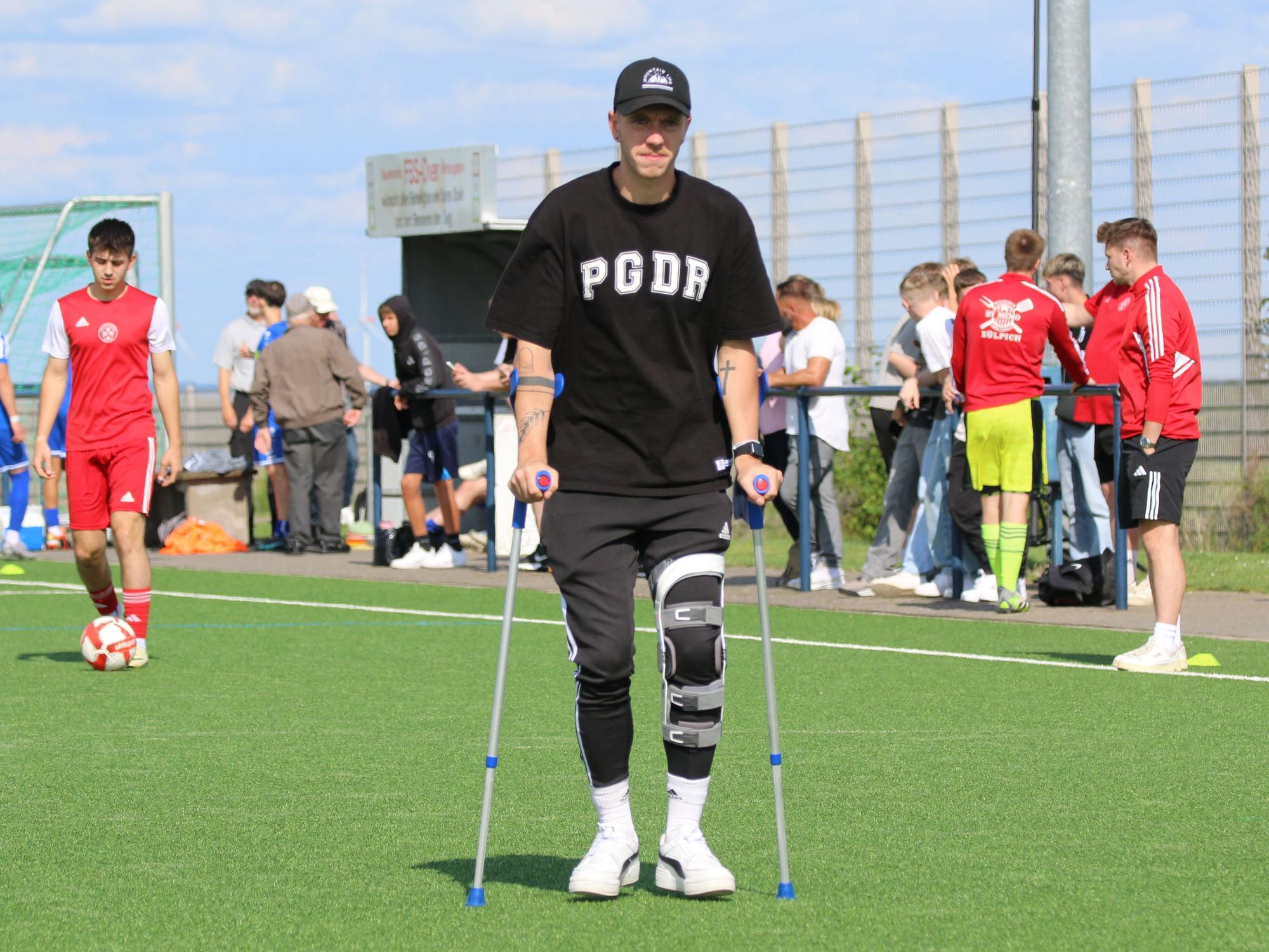 Stürmer Dominik Spies geht an Krücken vor einem Fußballspiel.