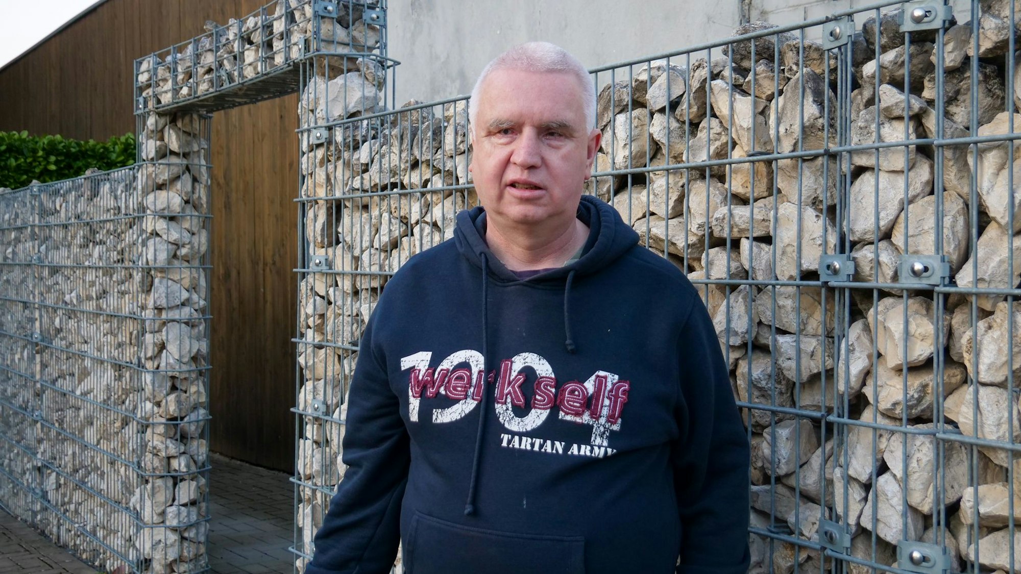 Ein Mann steht vor einer Mauer.