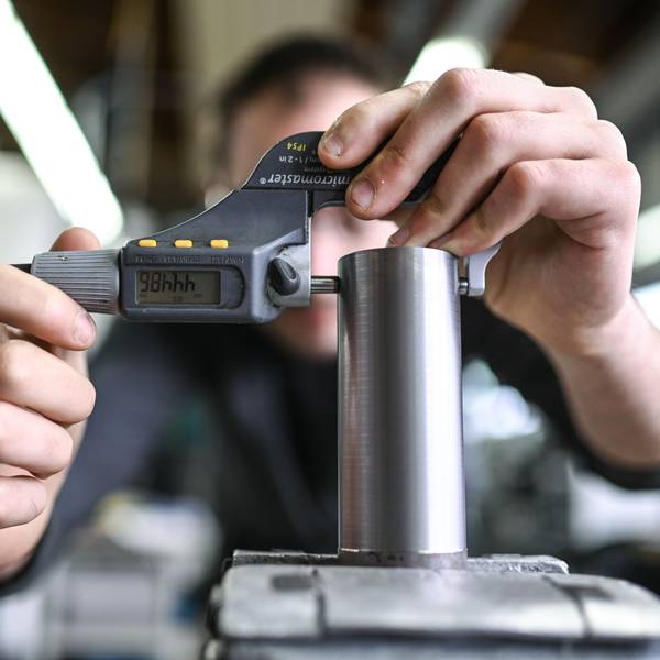 Ein Auszubildender im Metall-Handwerk misst in einem Ausbildungszentrum den Durchmesser eines Werkstücks.