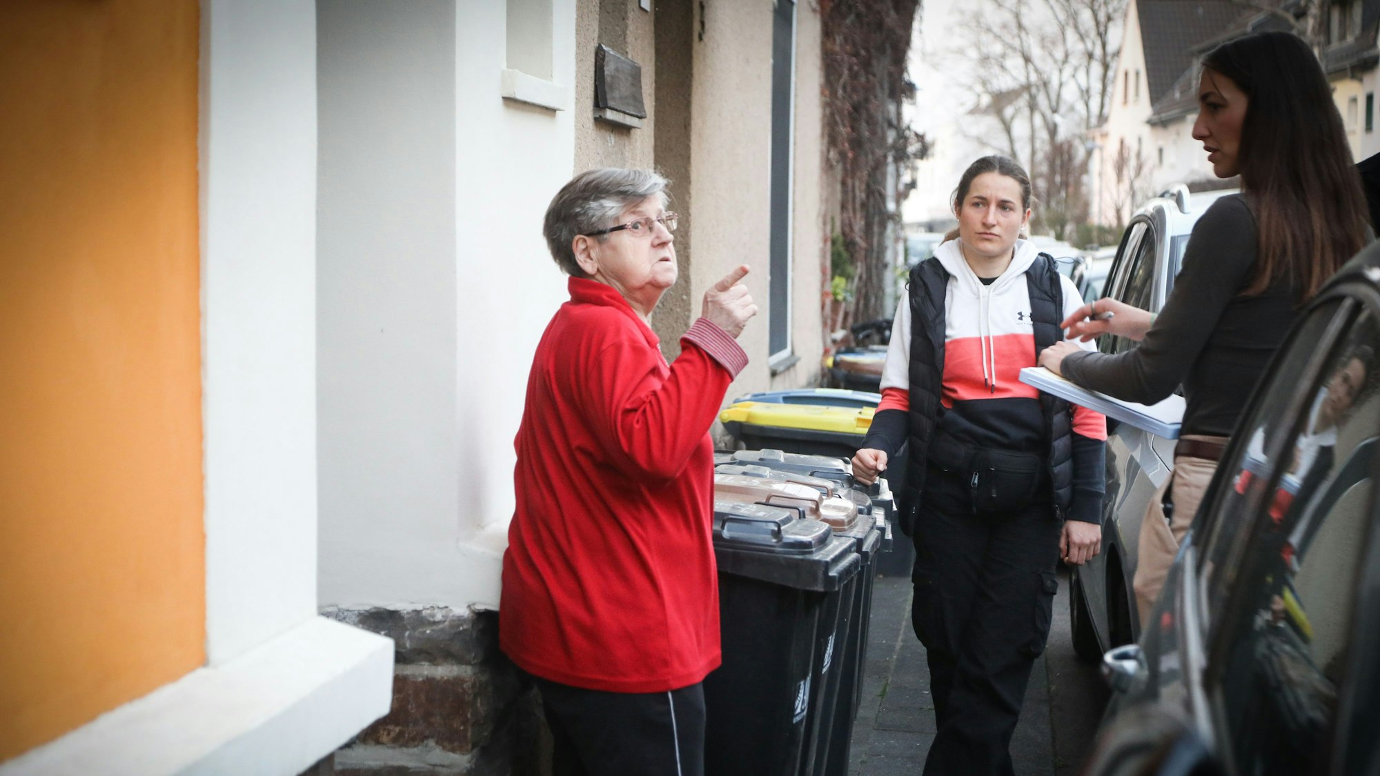 28.03.2025, Köln: Eine ältere Frau (l.)steht vor einem Hauseingang und zeigt auf etwas außerhalb des Bildausschnitts. Ihr gegenüber steht Kommissarin Carina mit einem Notizblock.