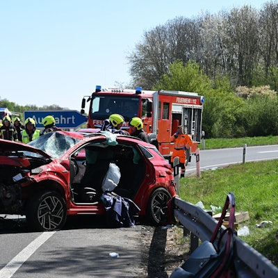 Das Bild zeigt Einsatzkräfte der Feuerwehr auf der Autobahn an einem verunglückten Auto.