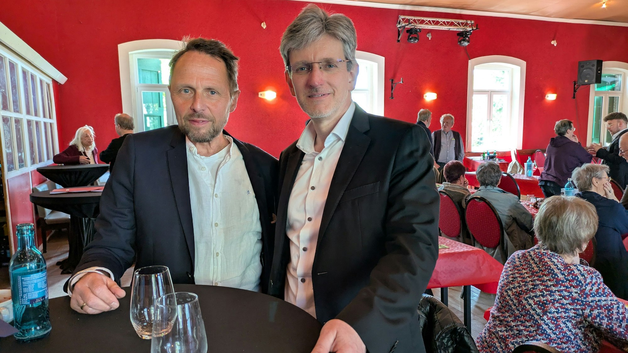 Zwei Männer stehen in einem Saal an einem Stehtisch.