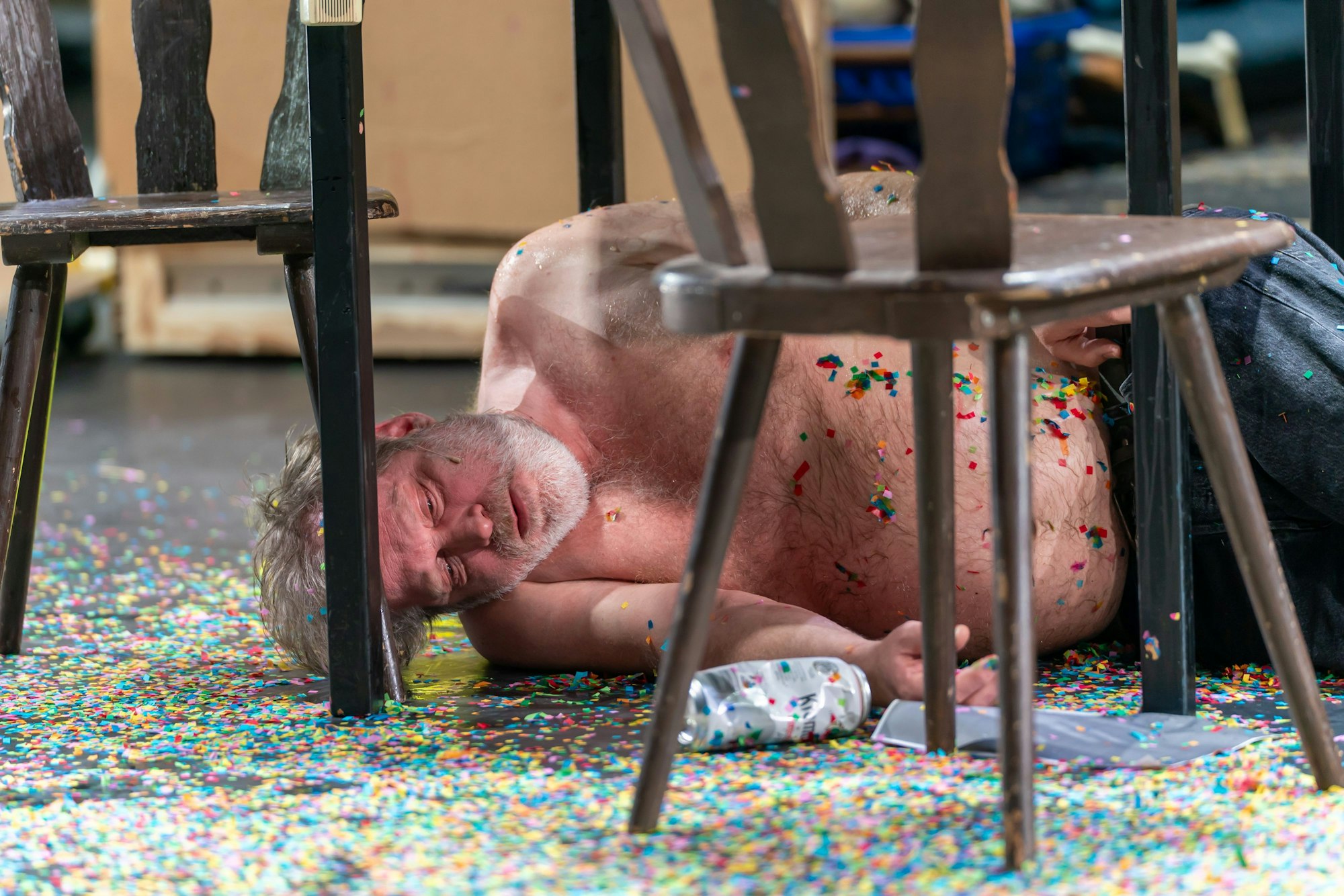 Jan Höppner liegt als Götz von Berlichingen mit freiem Oberkörper, scheinbar betrunken schlafend, unter einem Tisch.