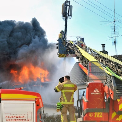 Von einer Drehleiter aus löschen Feuerwehrleute den Brand auf einem Bauernhof in Kall-Scheven.