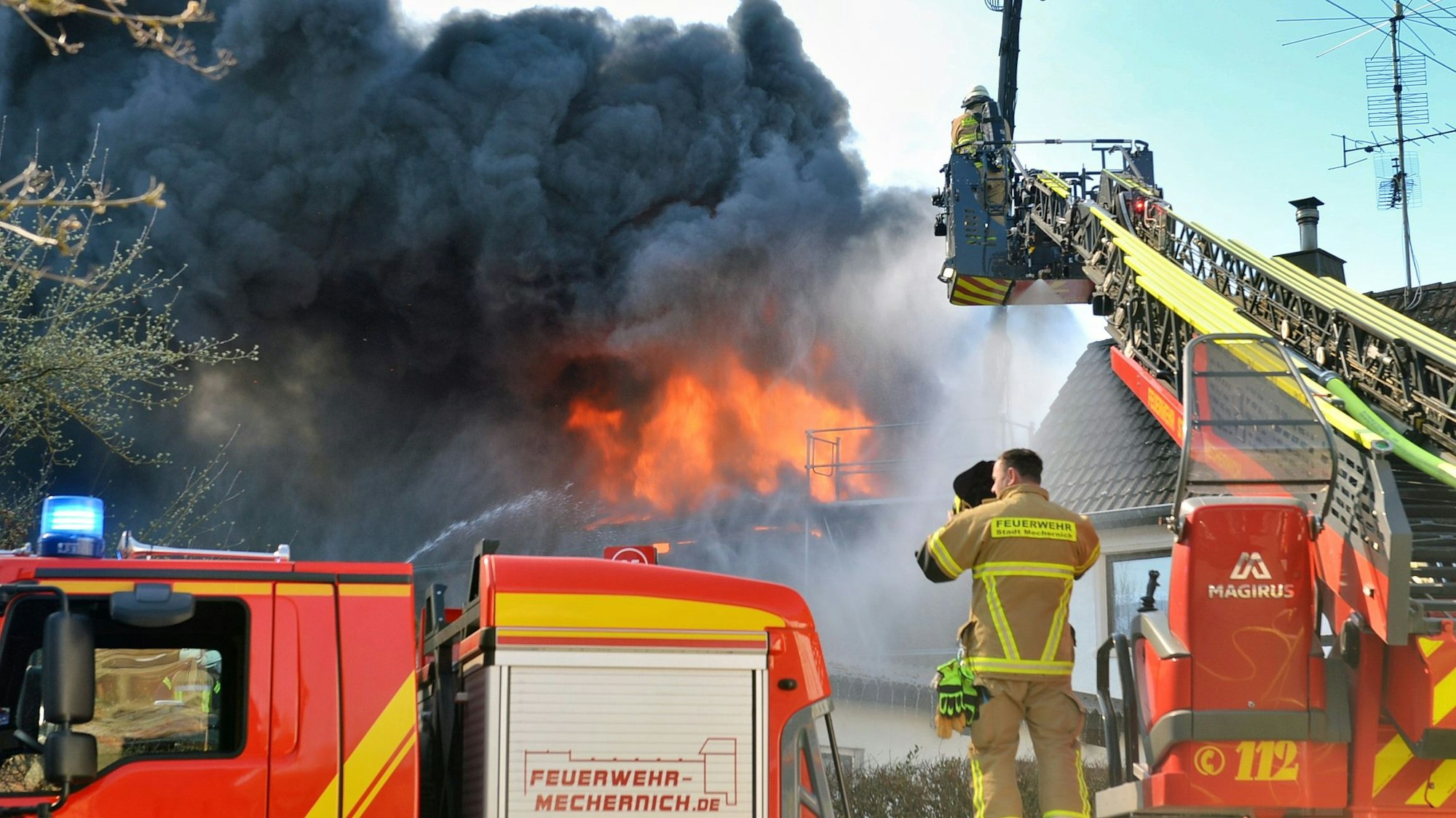 Von einer Drehleiter aus löschen Feuerwehrleute den Brand auf einem Bauernhof in Kall-Scheven.