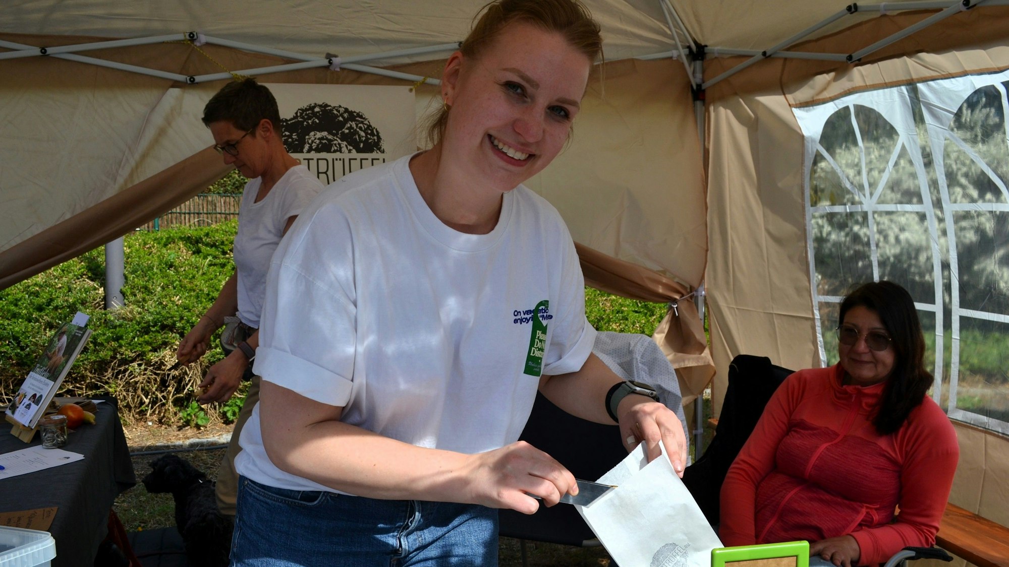 Eine junge Frau an einem Verkaufsstand, sie füllt eine kleine Papiertüte.