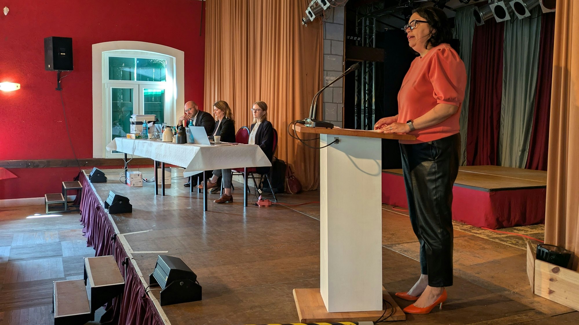 Eine Frau steht an einem Rednerpult auf einer Bühne.