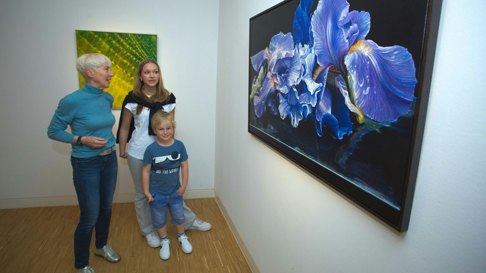 Eine Frau und zwei Kinder vor zwei Ölgemälden.