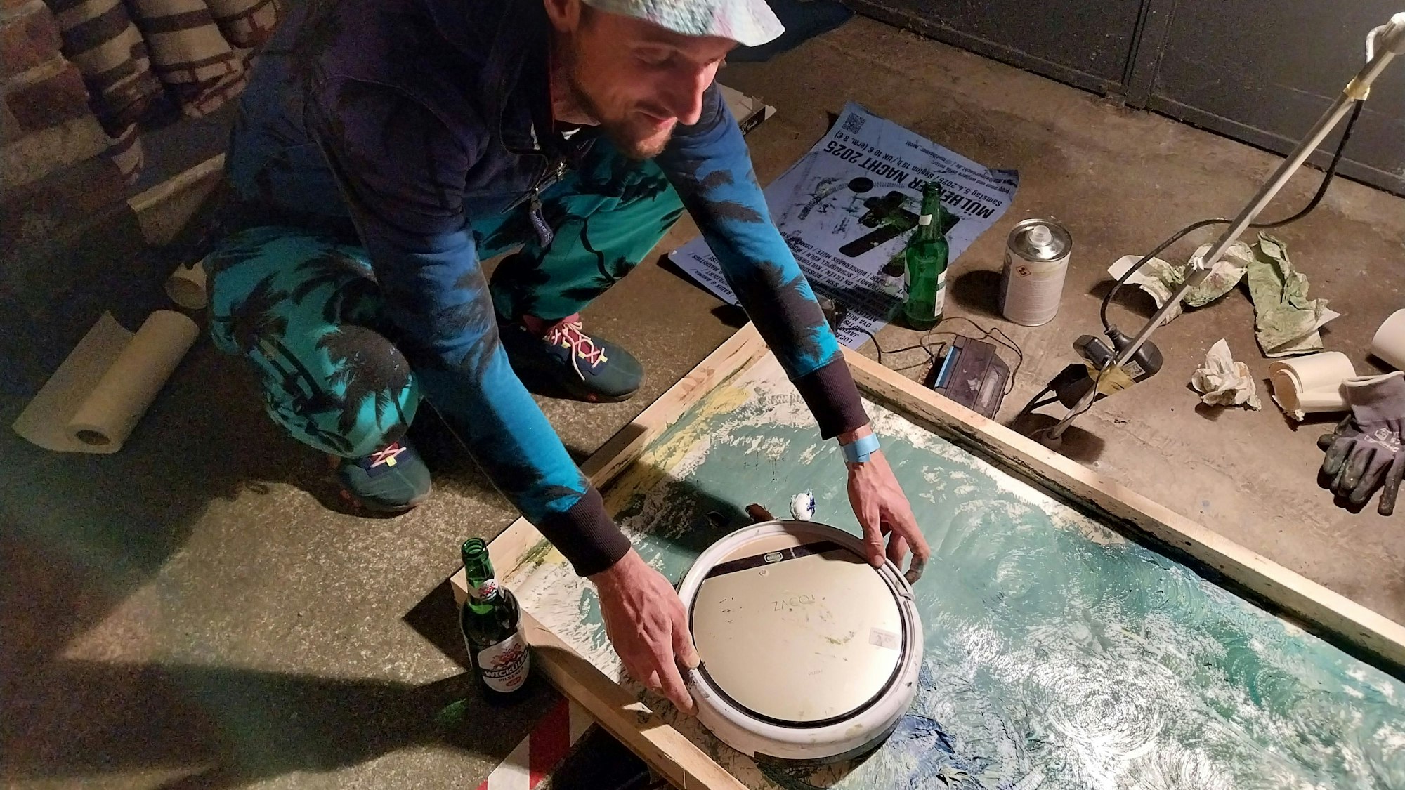 Ein Mann setzt einen Staubsaugerroboter auf eine Leinwand.