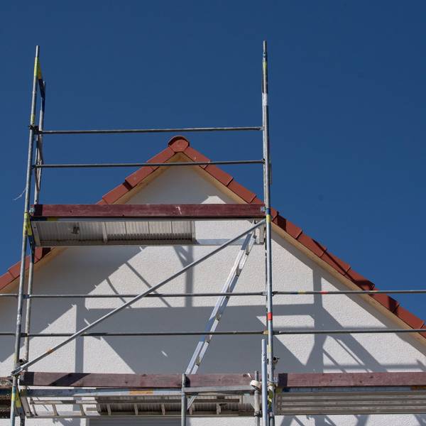 Gerüste stehen an einem Haus einer Neubausiedlung