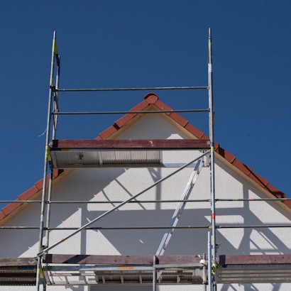 Gerüste stehen an einem Haus einer Neubausiedlung