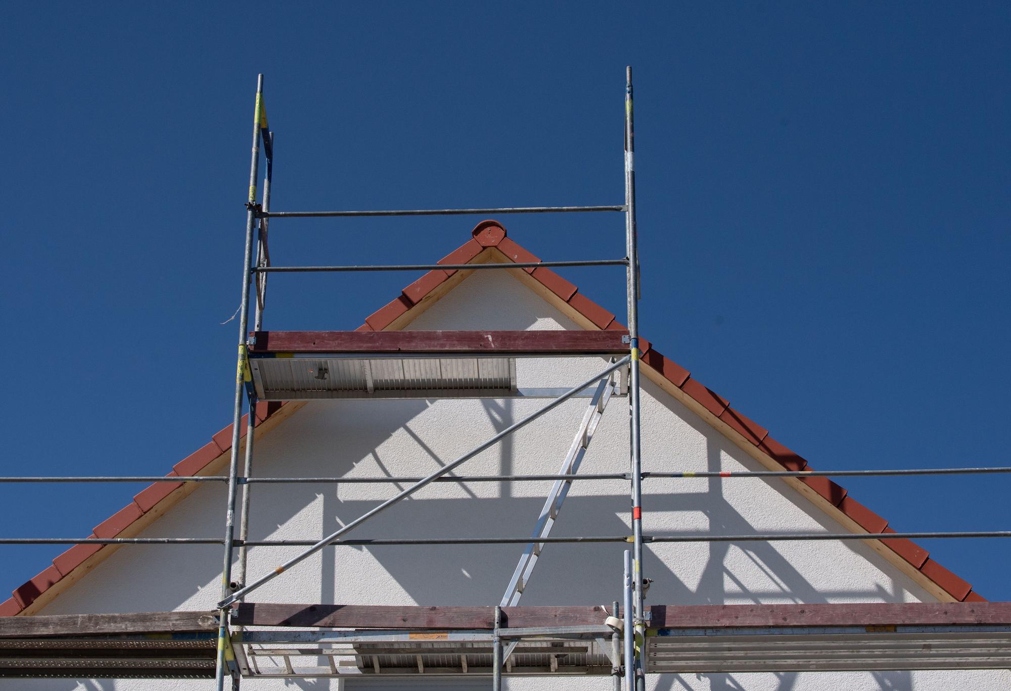 Gerüste stehen an einem Haus einer Neubausiedlung