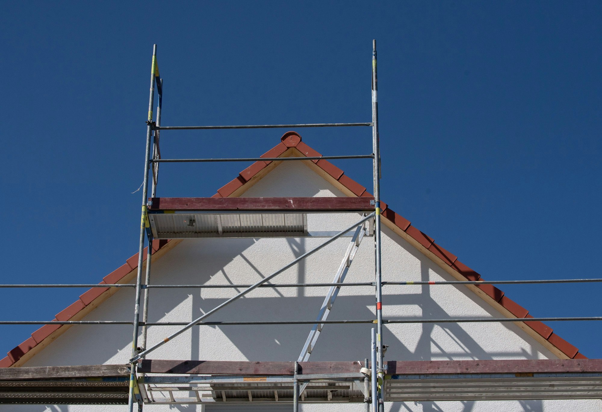 Gerüste stehen an einem Haus einer Neubausiedlung