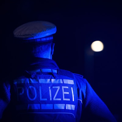 Ein Polizist steht neben einem Polizeifahrzeug (gestellte Szene).