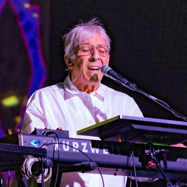 John Cale spielt Keyboard und singt auf der Bühne des Carlswerk Victoria. Er trägt ein weißes Hemd und Brille.