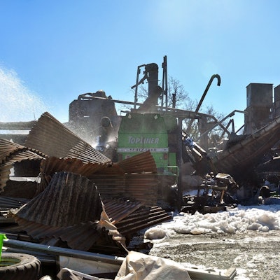 Das Heck eines grünen Mähdreschers ist in den Trümmern der Halle zu sehen, die in Kall-Scheven niedergebrannt ist.