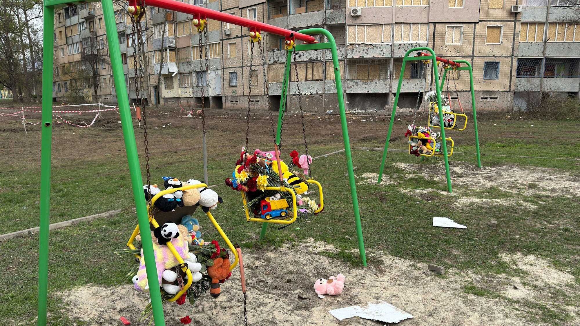 Blumen und Kuscheltiere liegen auf einem Spielplatz in Krywyj Rih.