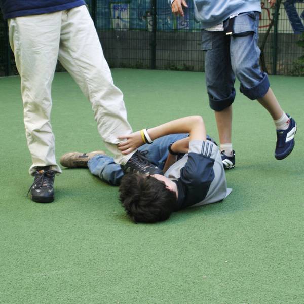 Zwei Jugendliche treten auf einen am Boden liegenden Jungen ein.