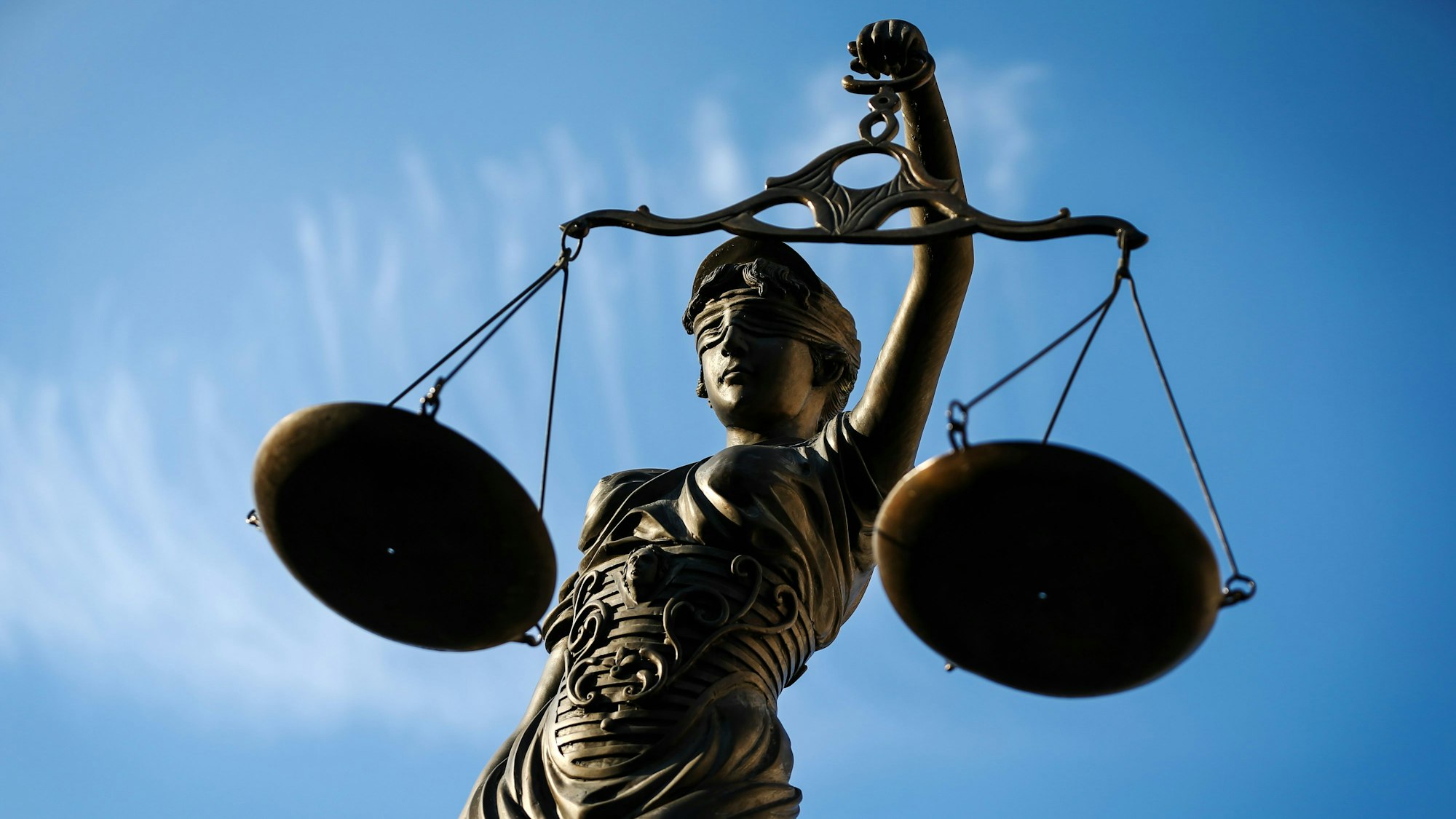 Eine Justitia-Skulptur hält zwei Waagschalen hoch.