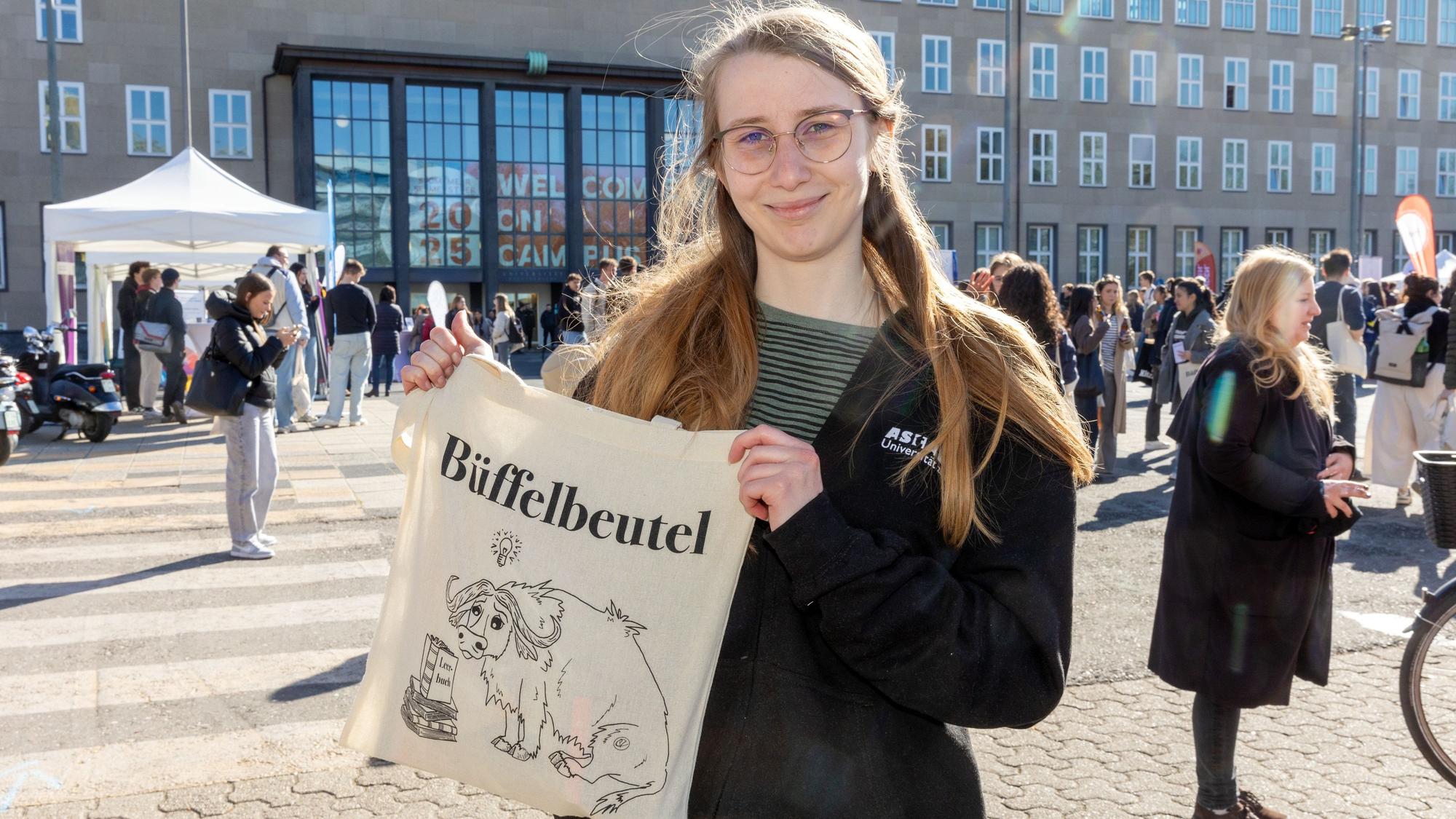 Leonie Bandel vom Asta mit dem Ersti-Beutel: Der enthält Gutscheine fürs Bootshaus, Magazine und sonstige Infos und Give-Aways von Kölner Sponsoren. Auf dem Beutel: ein trauriger Büffel, der für den hohen Leistungsdruck steht.
