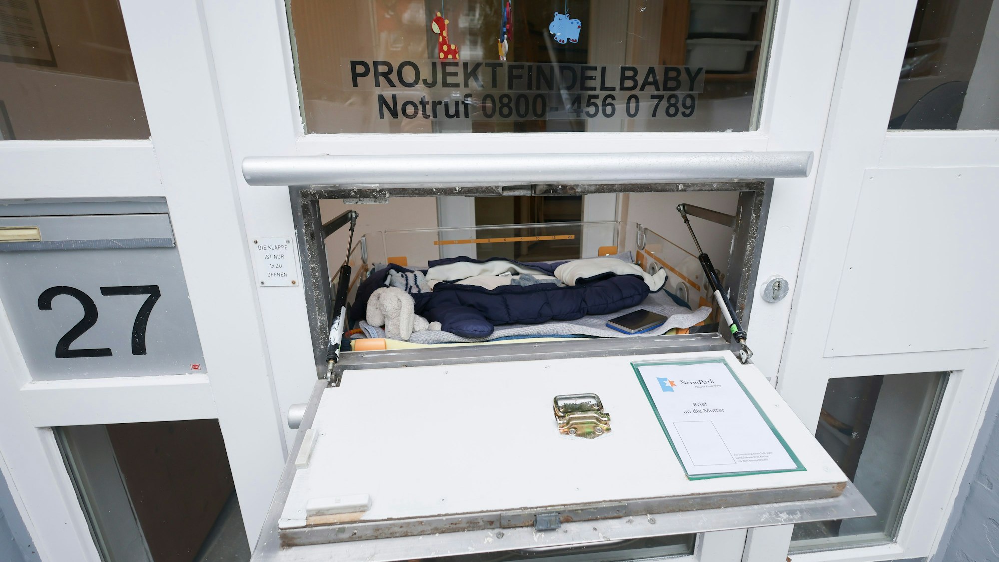 PRODUKTION - 25.03.2025, Hamburg: Eine Babyausstattung mit Schlafsack, Strampelanzug, Mütze und Kuscheltieren liegt in einem Wärmebett der Babyklappe im Kinderhaus Goethestraße in Hamburg-Altona. Im Kinderhaus Goethestraße ist vor 25 Jahren die erste Babyklappe Deutschlands eröffnet worden. (zu dpa: «25 Jahre Babyklappe: «Es geht darum, Leben zu retten»») Foto: Christian Charisius/dpa +++ dpa-Bildfunk +++