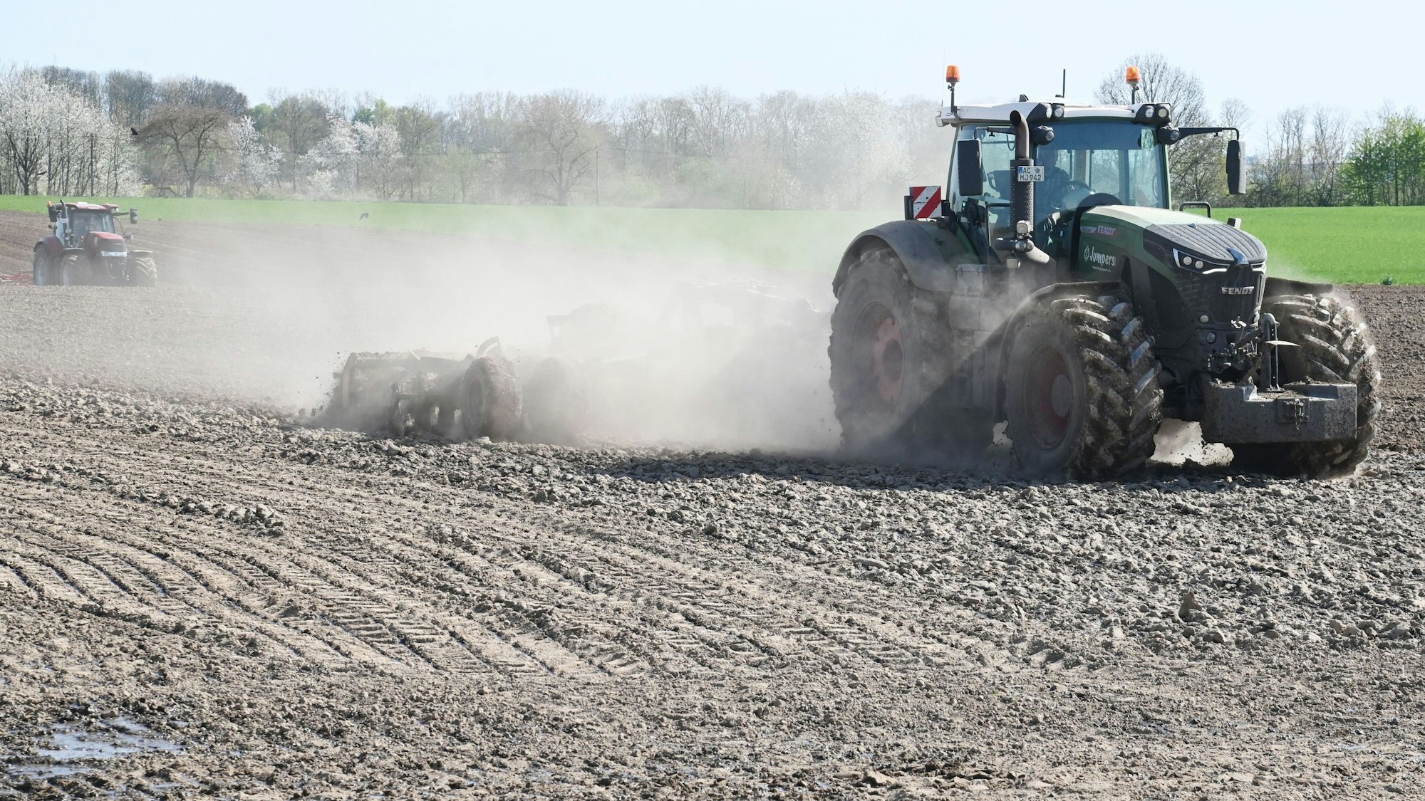 Zwei Traktoren auf einem Acker im Kölner Norden. Im letzten Jahr ähnelten die Kölner Acker einer Seenlandschaft, nun verstauben sie.
