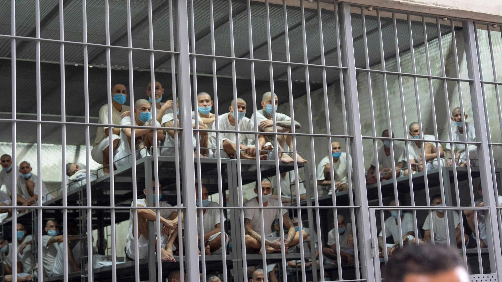 Gefangene schauen aus ihrer Zelle, während Heimatschutzministerin Kristi Noem das Terroristengefängnis in Tecoluca, El Salvador, besichtigt.