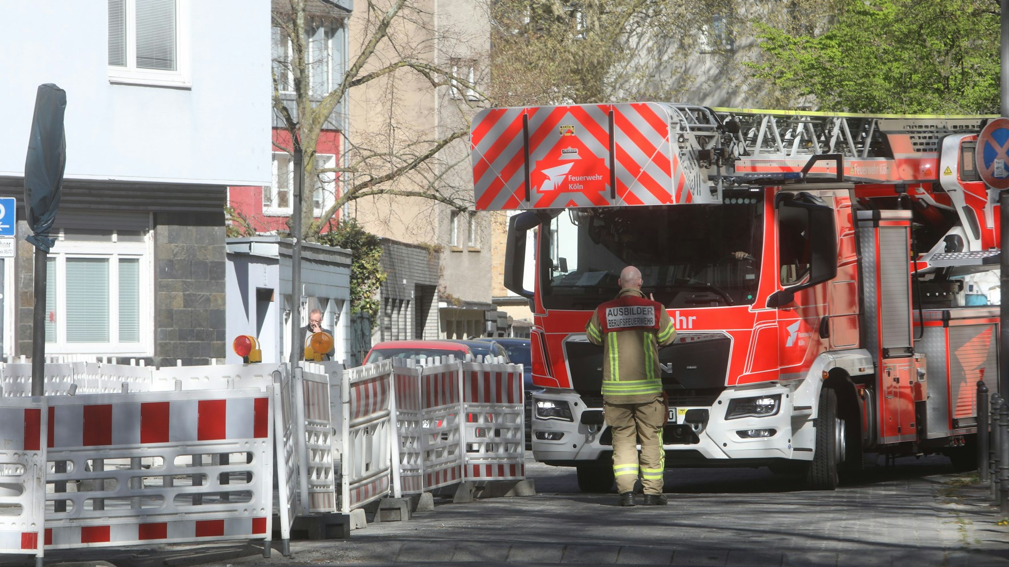 Ein Drehleiterfahrzeug versucht, in eine enge Straße abzubiegen. Vor dem Fahrzeug steht ein Feuerwehrmann.